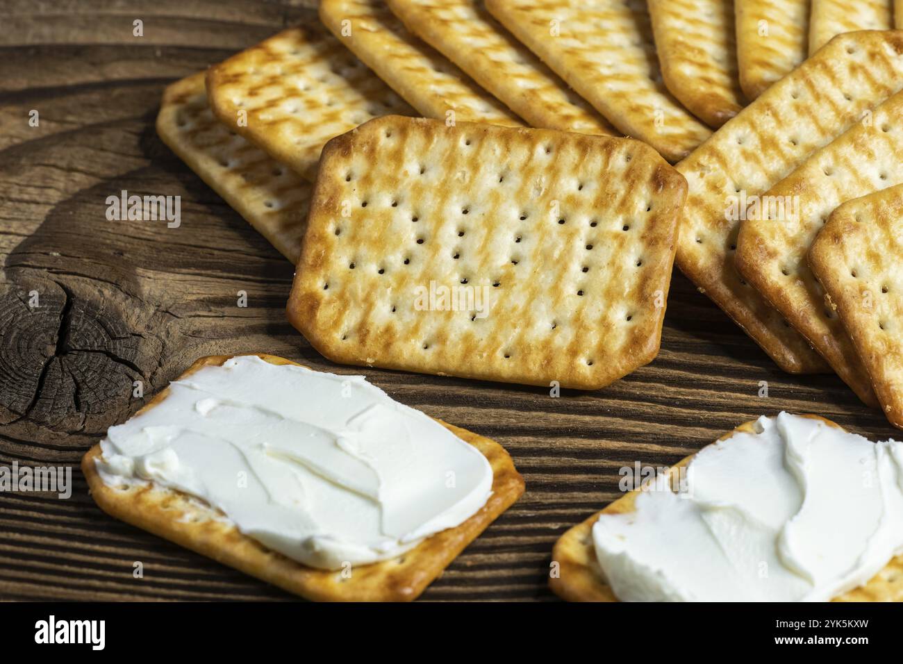 Cracker verteilen sich mit Käse als leichte Zwischenmahlzeit auf einem Holzbrett Stockfoto