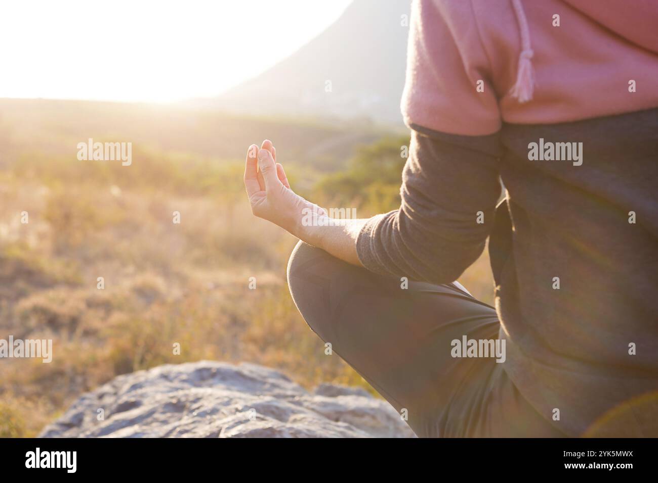Eine Frau sitzt auf einem Felsen in der Lotusposition mit geschlossenen Fingern in einem Zeichen der Harmonie, Entspannung und Meditation. Yoga, selbst-Immersion, Balance wi Stockfoto