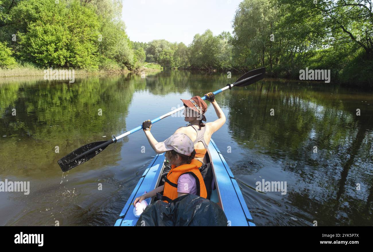 Familien-Kajakausflug. Mutter und Tochter rudern mit einem Boot auf dem Fluss, eine Wasserwanderung, ein Sommerabenteuer. Umweltfreundlicher und extremer Tourismus, aktiv und gesund Stockfoto