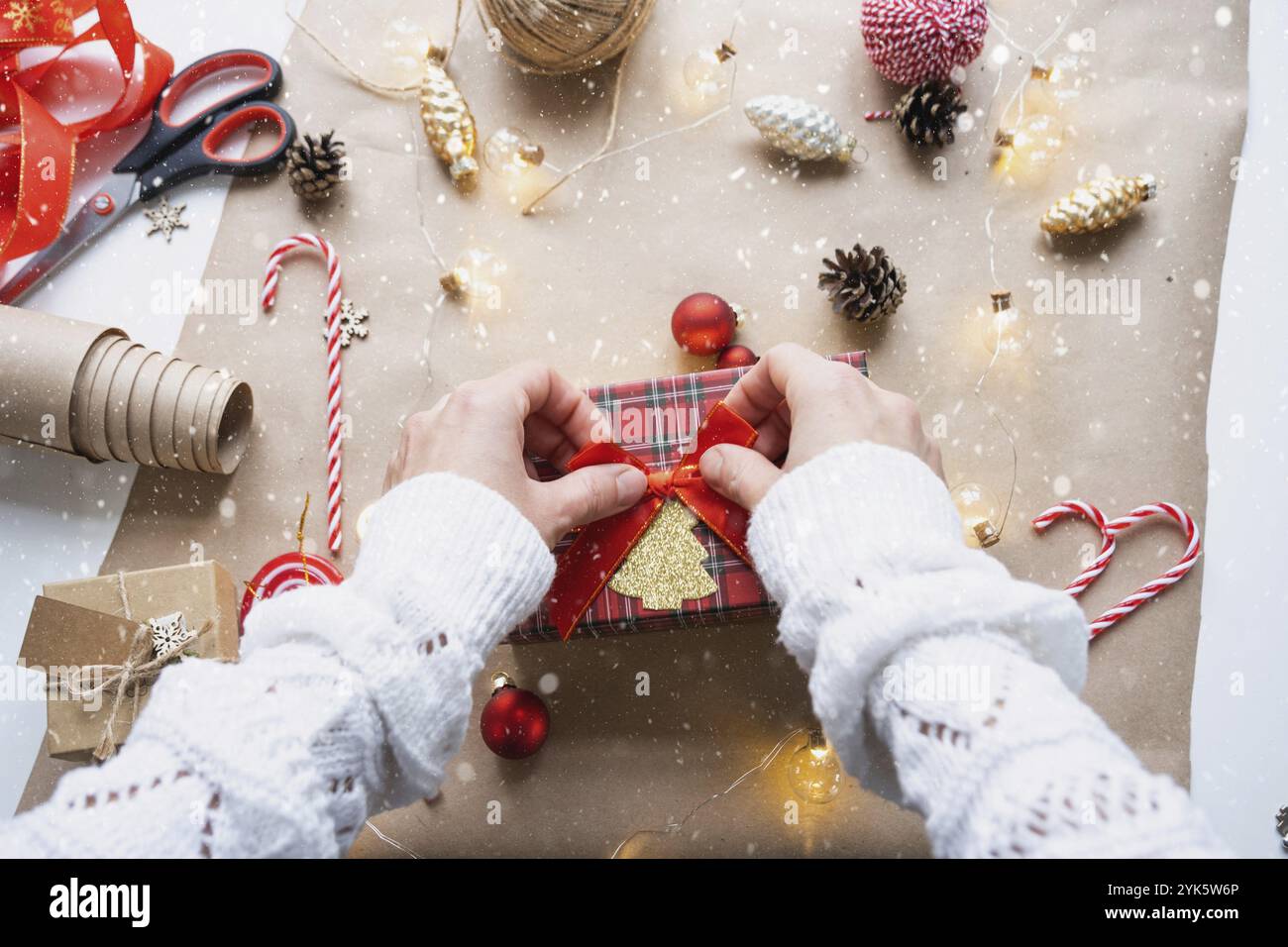 Packen Sie ein Geschenk für Weihnachten und Neujahr in Kraftpapier, Kegel, Klebeband, Schere. Tags mit Mock-up, natürliches Dekor, handgemacht, DIY. Festliche Stimmung. Flach Stockfoto