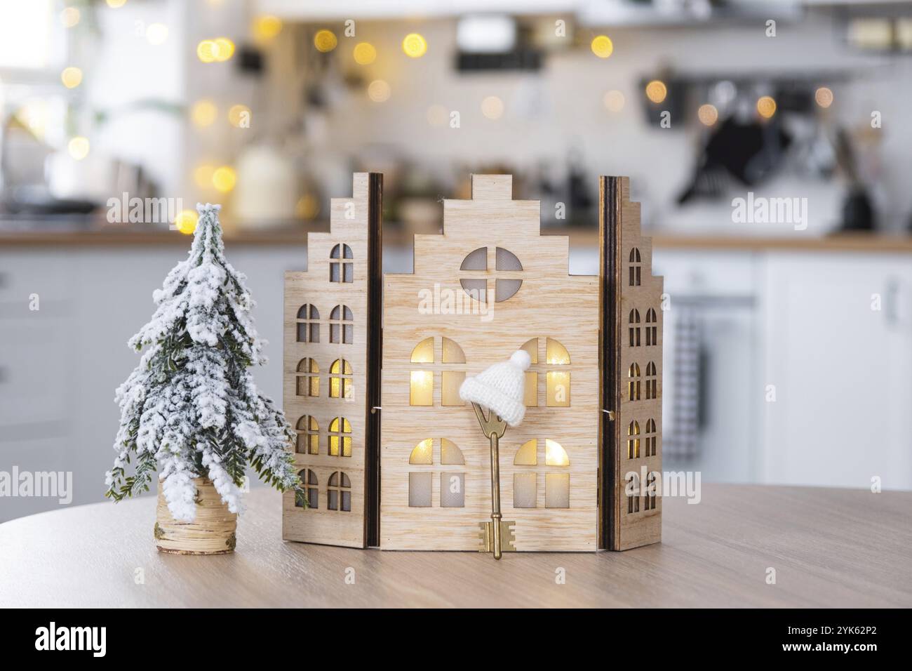 Schlüssel und winziges Haus von kleiner Größe auf gemütlichem Haus mit Weihnachtsdekor auf dem Tisch der festlichen weißen Küche. Geschenk für Neujahr. Versicherung, zieht in eine neue Ho Stockfoto