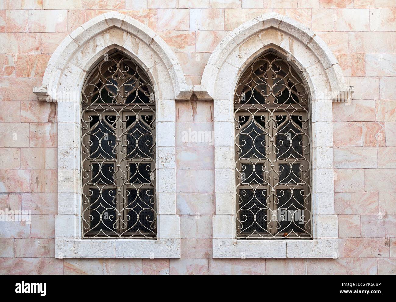 Ein wunderschön gefertigtes gotisches Fenster ziert eine alte Steinmauer mit künstlerischen Metallarbeiten. Stockfoto Ein wunderschön gefertigtes gotisches Fenster ziert eine alte Steinmauer mit künstlerischen Metallarbeiten. Stockfoto