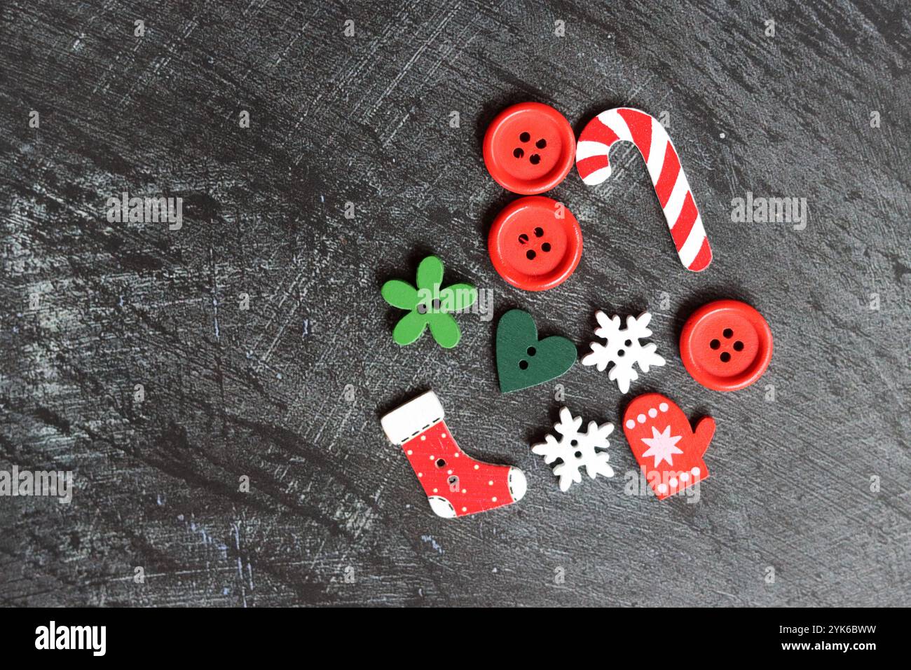 Holzknöpfe in verschiedenen Formen auf dunklem strukturiertem Hintergrund mit Kopierraum. Weihnachtsdekoration aus nächster Nähe. Basteln Sie Vorräte auf einem Schreibtisch. Stockfoto