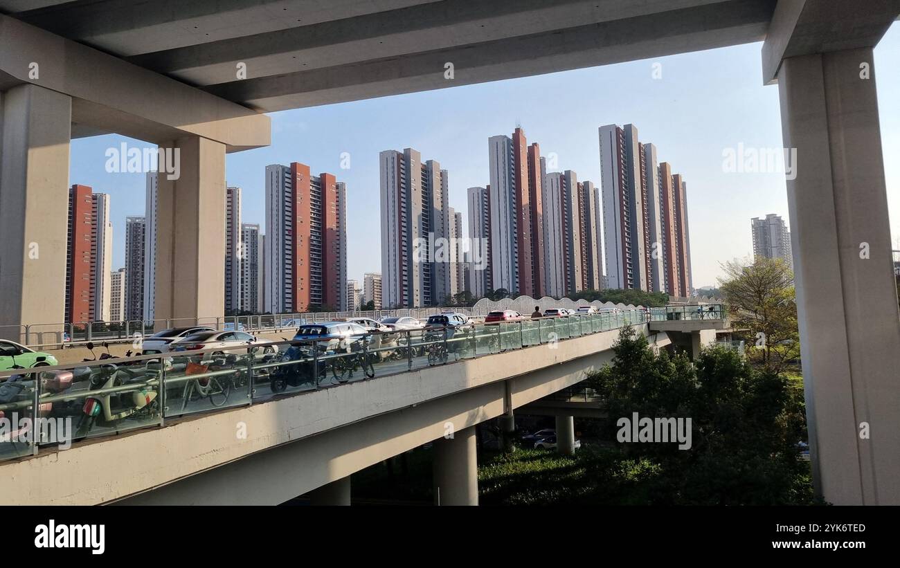 Eine urbane Szene aus Shenzhen, China, zeigt eine geschäftige Überführung mit Autos und Motorrädern vor dem Hintergrund moderner Hochhäuser. Stockfoto