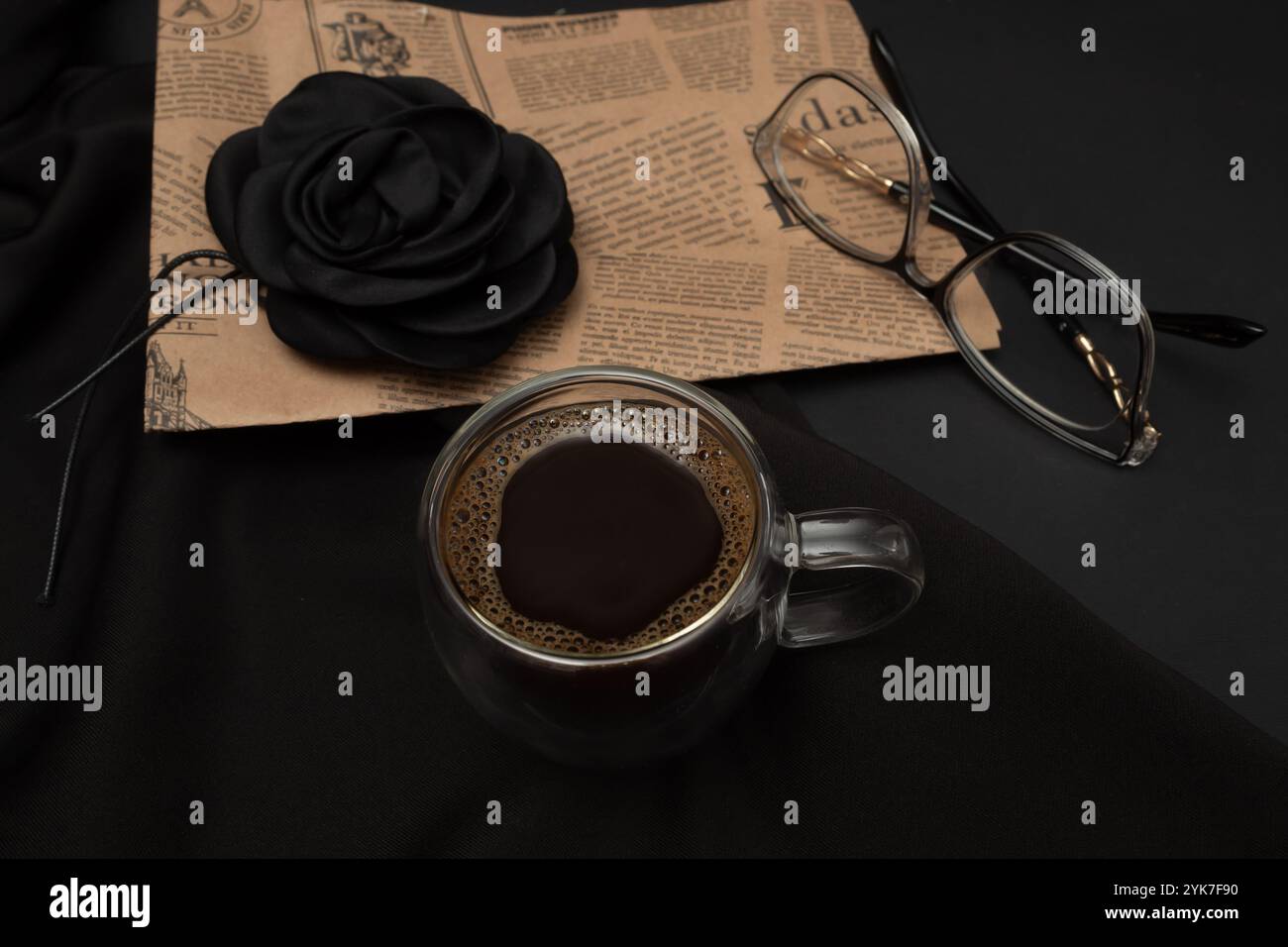 Schwarzer Kaffee in einer beleuchteten Tasse mit zusätzlichen Elementen und schwarzem Hintergrund. Stockfoto