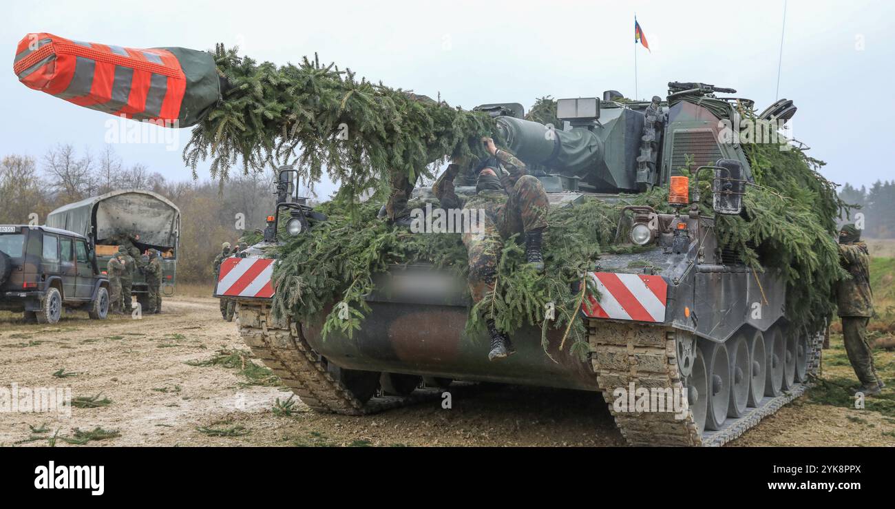 Deutsche Heeressoldaten, die der 295. Französisch-deutschen Brigade zugewiesen wurden, tarnen einen PzH 2000 A1 in Vorbereitung auf eine Live-Feuerübung während der Dynamischen Front 25 auf dem Trainingsgelände Grafenwöhr, Bayern, 17. November 2024. Dynamic Front findet vom 4. Bis 24. November in Finnland, Estland, Deutschland, Polen und Rumänien statt. und zeigt, dass die NATO in der Lage ist, Zielinformationen und operative Grafiken von der Arktis bis zum Schwarzen Meer auszutauschen. Sie erhöht die Letalität der Allianz durch Fernbrände, baut die Einsatzbereitschaft in einem komplexen gemeinsamen, multinationalen Umfeld auf und nutzt Host-n Stockfoto