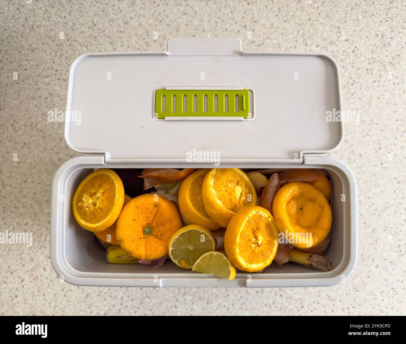 Ein Behälter mit geöffnetem Deckel voll mit Haushaltsresten aus biologischem Anbau, einschließlich Obst und Gemüse, die kompostiert oder verantwortungsvoll entsorgt werden können Stockfoto