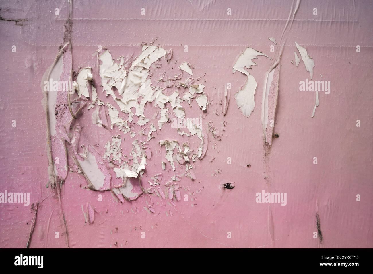 Zerkratzter rosafarbener Aufkleber auf der Wandstruktur Stockfoto