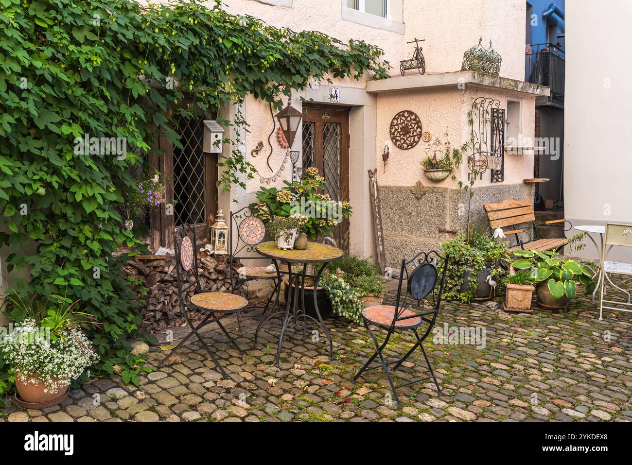 Idyllischer Sitzbereich mit Eisentisch und Stühlen vor einem Haus in einer Gasse in der Altstadt von Bremgarten, Kanton Aargau, Schweiz Stockfoto