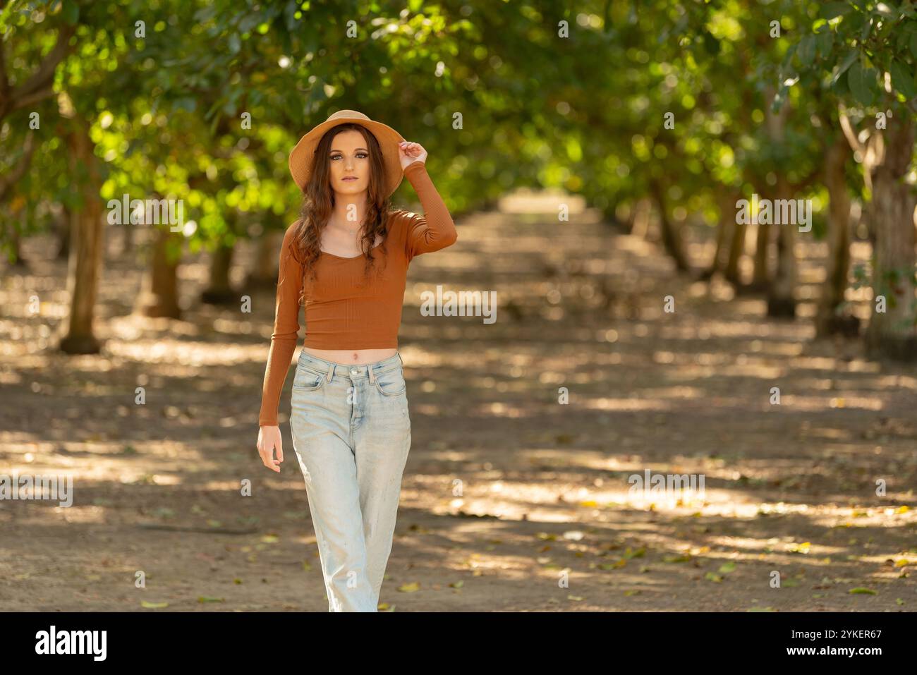 Frau, die einen Hut im Obstgarten auf einer rustikalen Farm trägt Stockfoto