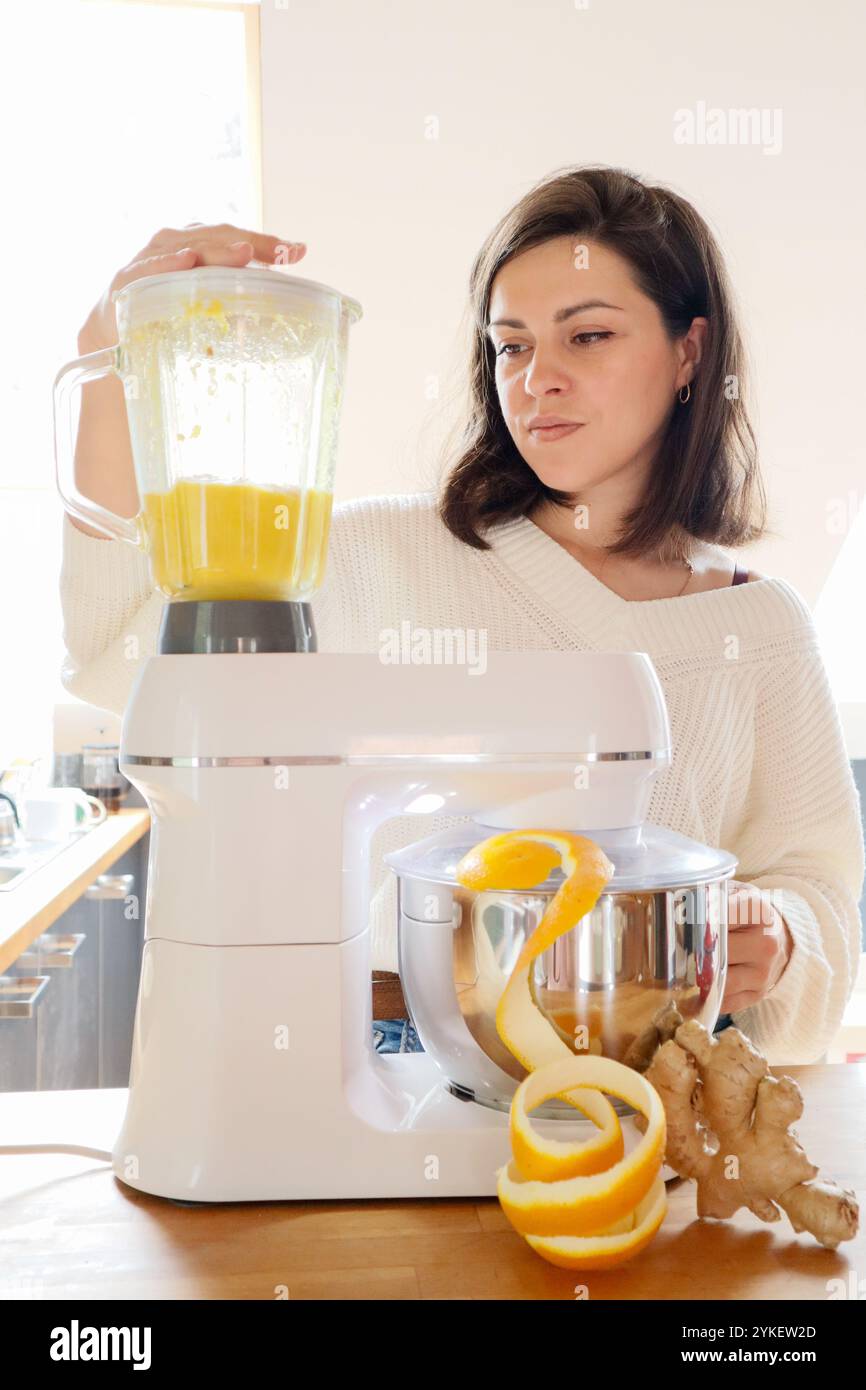 Eine Frau mahlt Orangen und Ingwer in einer Küchenmaschine Stockfoto