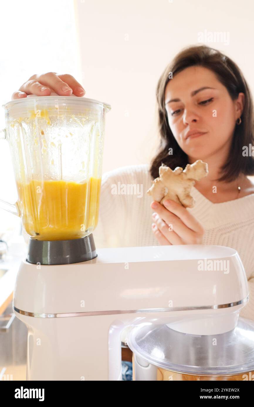 Eine Frau mahlt Orangen und Ingwer in einer Küchenmaschine Stockfoto