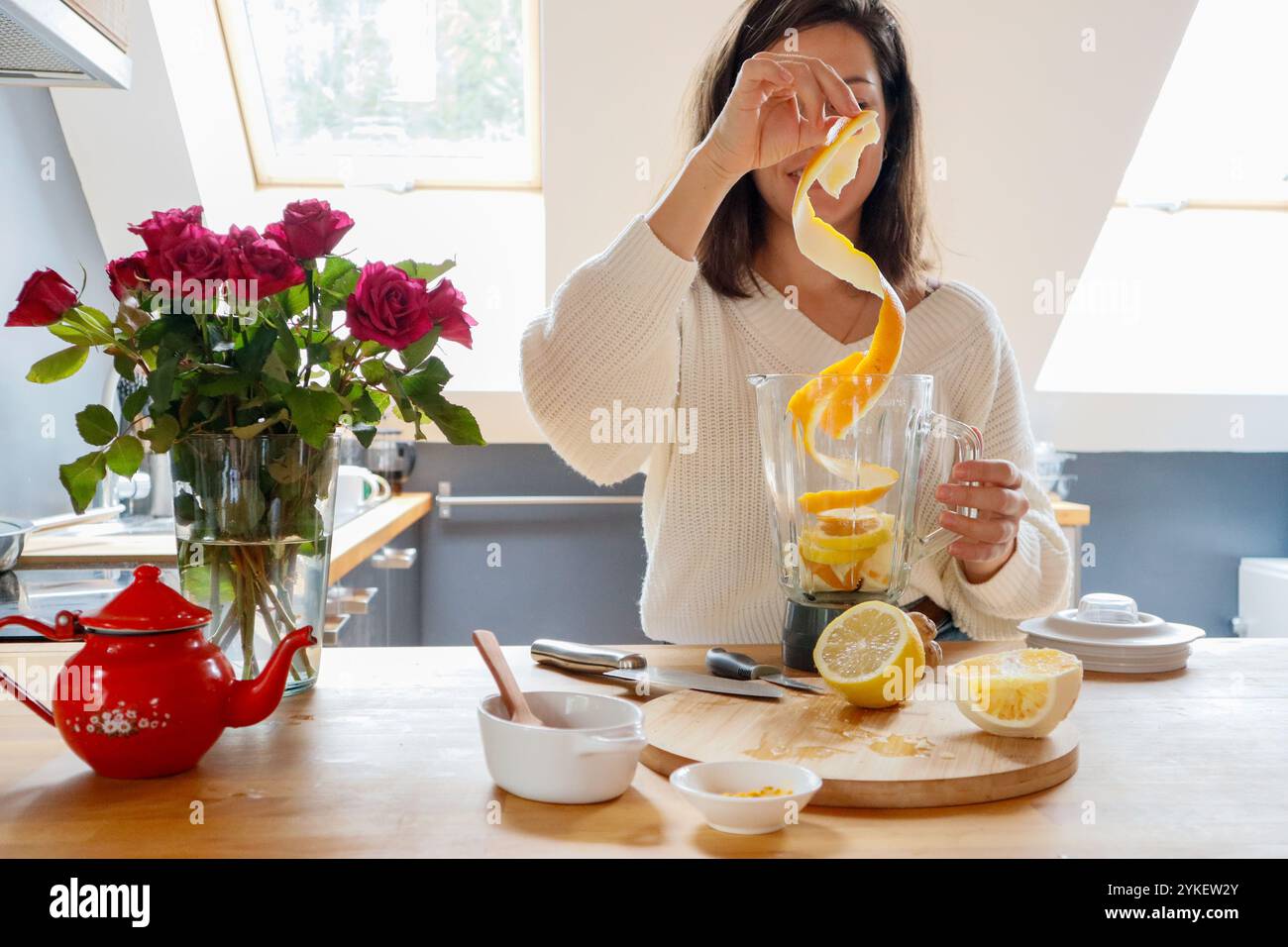 Eine Frau fügt Zitrone, Kurkuma, Ingwer, Orange und Honig in einen Mixer Stockfoto