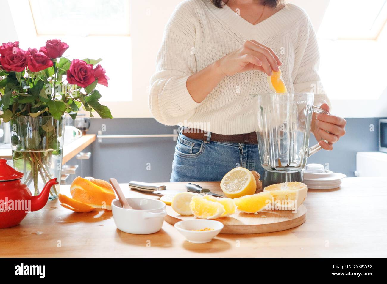 Eine Frau fügt Zitruszutaten für Tee in einen Mixbecher Stockfoto