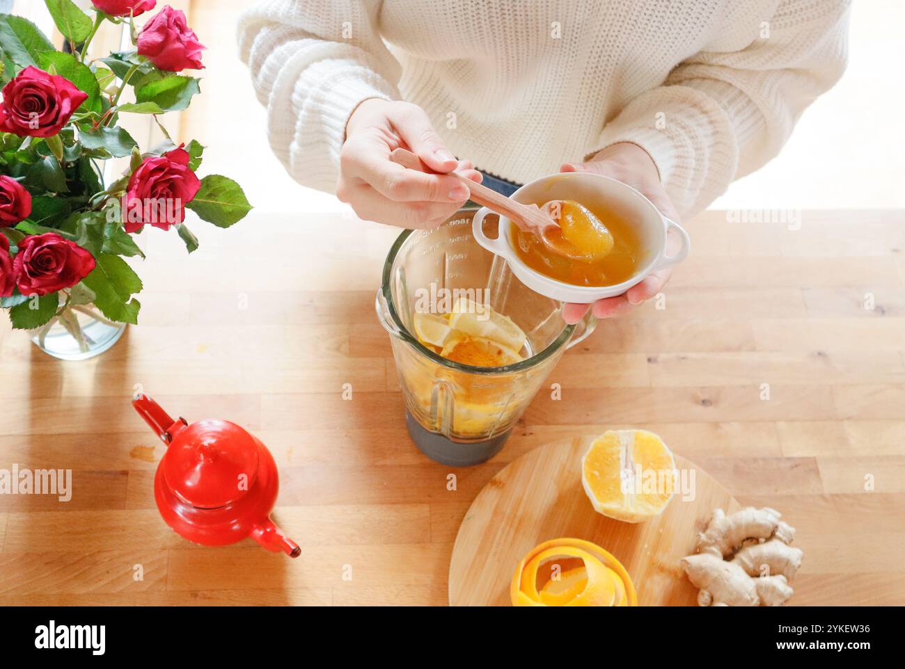 Draufsicht - mit den Händen Honig in den Mixer mit Zitrusfrüchten für Tee geben Stockfoto