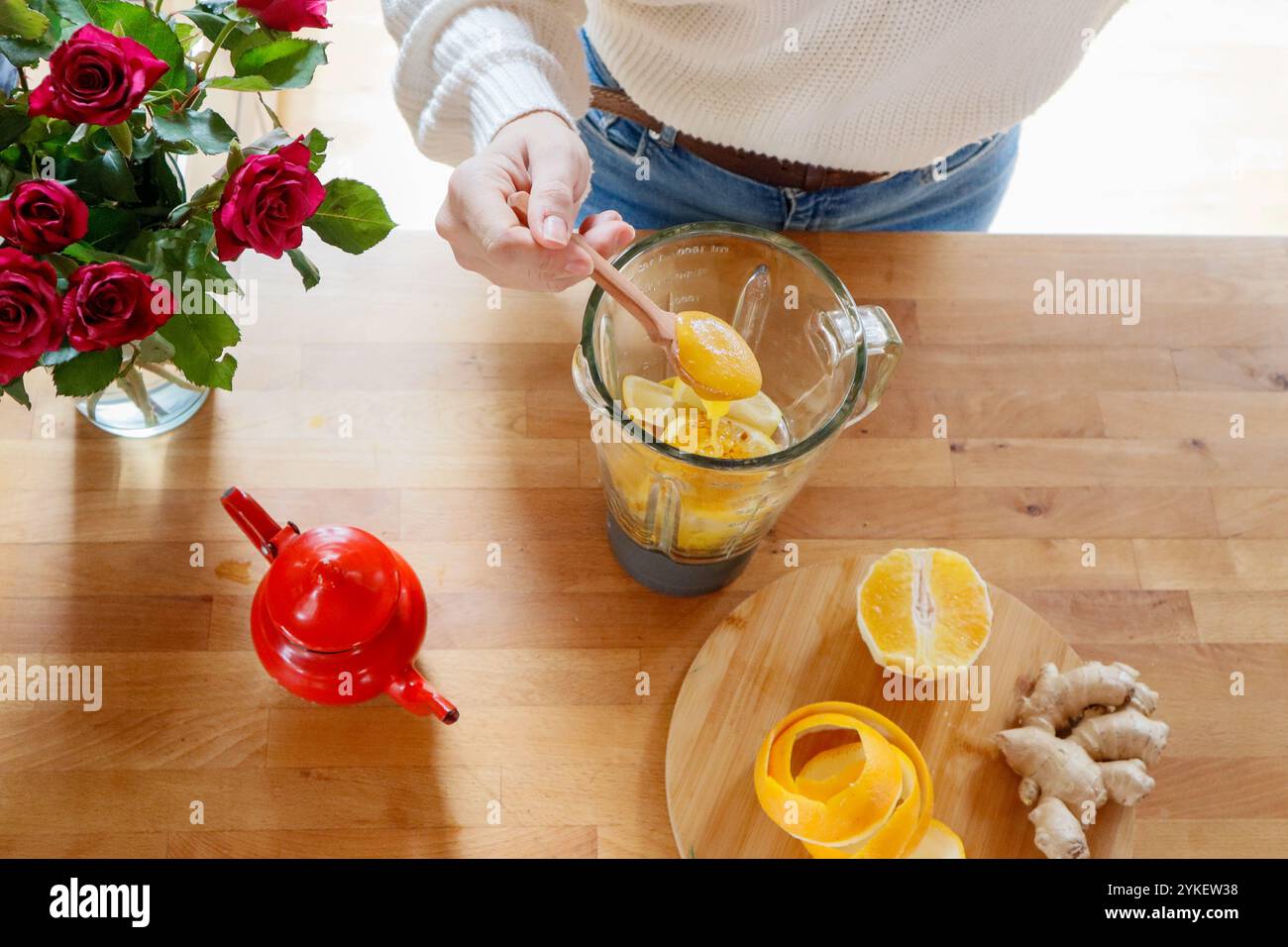Mit den Händen Honig in den Mixer mit Orange und Ingwer für Tee geben Stockfoto