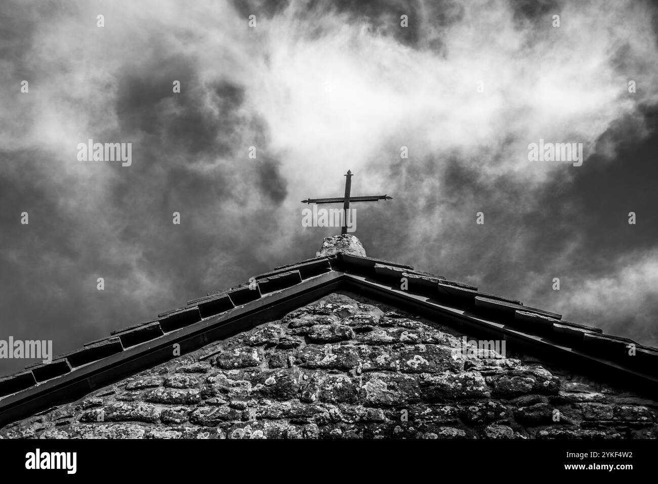 Kleines eisernes Kreuz auf dem Dach der Kirche San Michele Arcangelo gegen den blauen Himmel und die weißen Wolken in Chiusi Della Verna, Arezzo, Toskana, I Stockfoto
