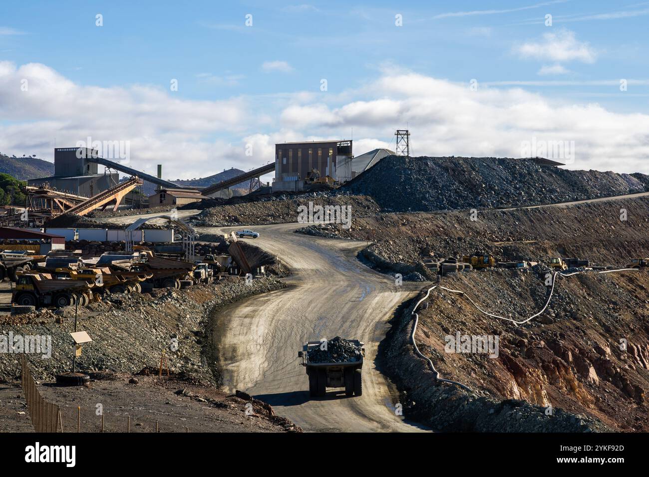 Eine geschäftige Mine Rio Tinto in Huelva, Spanien, mit schweren Maschinen, Erzhaufen und Bergbauinfrastruktur unter blauem Himmel. Stockfoto