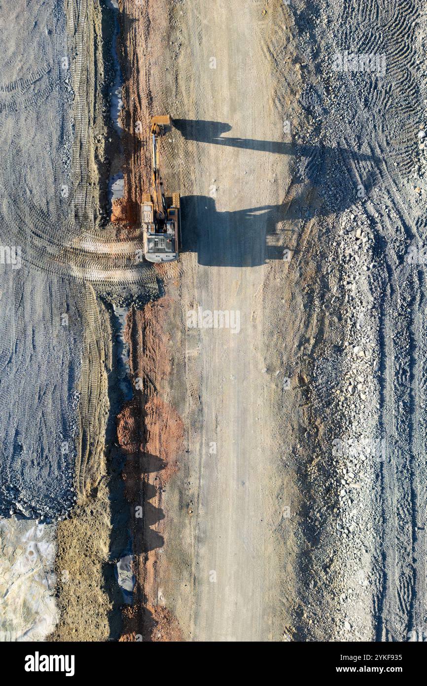 Die Luftaufnahme erfasst einen großen Bagger, der in den weiten, strukturierten Landschaften der Mine Rio Tinto in Huelva, Spanien, am Werk ist und die Größe des Mini-Geräts unterstreicht Stockfoto