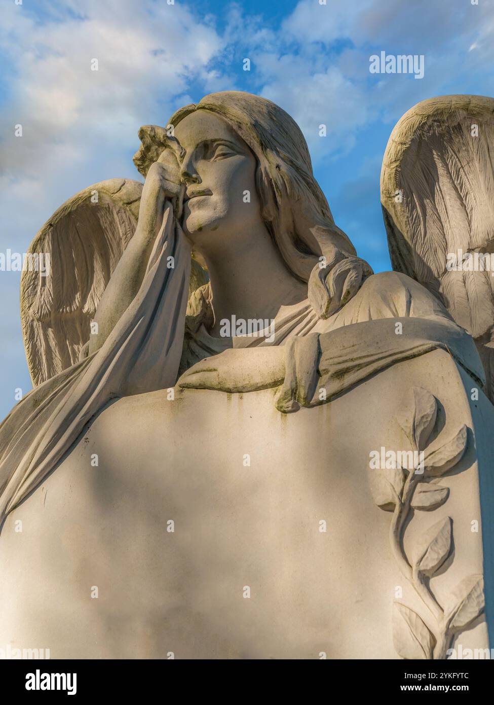 Nahaufnahme der Trauerengelstatue aus weißem Stein auf Grabstein vor dem blauen Himmel Stockfoto