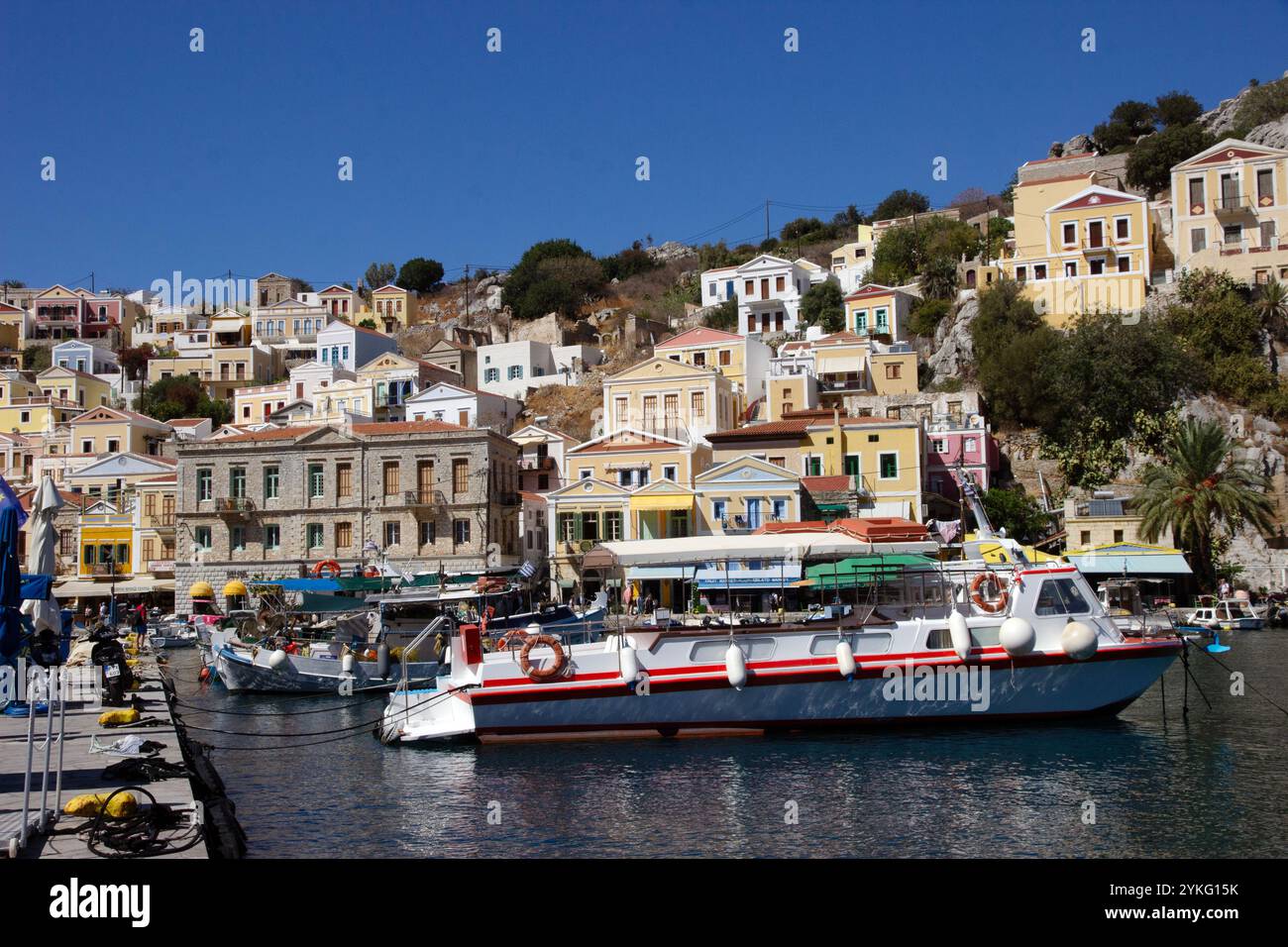 Der Hafen von Symi Stadt auf der griechischen Insel Symi in der dodekanesischen Inselkette mit seinen farbenfrohen Häusern im neoklassizistischen Stil. Stockfoto