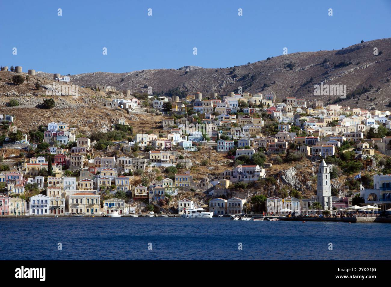 Der Hafen von Symi Stadt auf der griechischen Insel Symi in der dodekanesischen Inselkette mit seinen farbenfrohen Häusern im neoklassizistischen Stil. Stockfoto