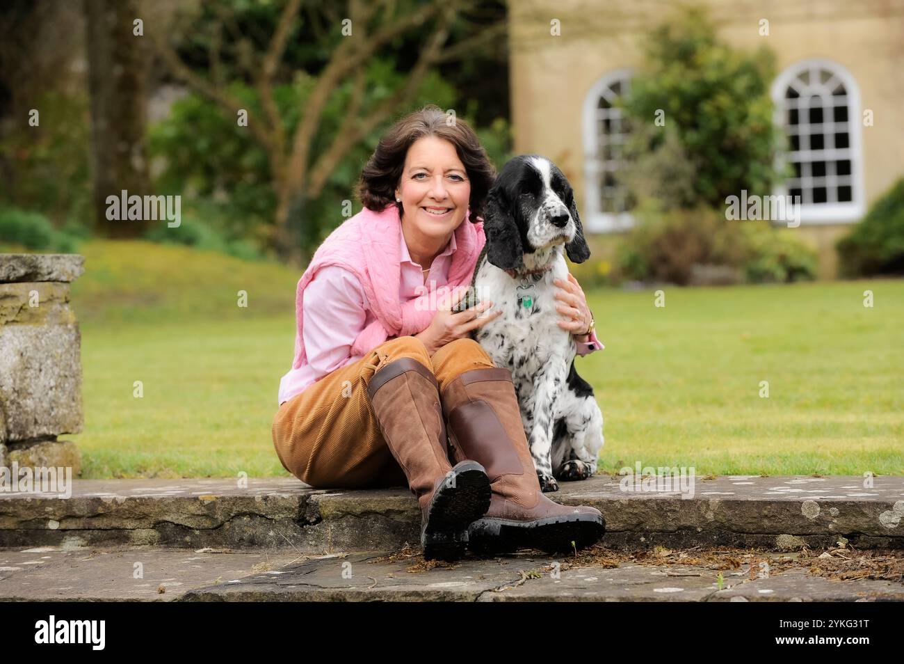 Eine Frau mittleren Alters saß und streichelte ihren älteren Cocker Spaniel Hund. Stockfoto