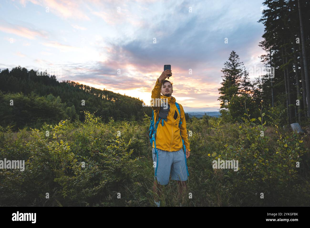 Wanderer in einer gelben Jacke bei Sonnenuntergang in den Beskiden, Tschechien. Erleben Sie Abenteuer und fangen Sie den Moment in der Natur ein Stockfoto