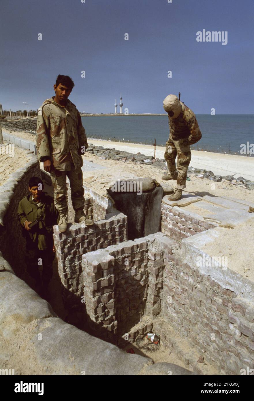 Erster Golfkrieg: 11. März 1991 saudische Soldaten erkunden einen verlassenen irakischen Graben am Strand Ali Baba in Kuwait City. In der Erwartung, dass die Koalitionstruppen vom Meer aus einmarschieren, wurden Stacheldraht und Anti-Landungsboote am Strand und in den seichten Gewässern nahe der Küste aufgestellt. Auch die Strände wurden abgebaut. Im Hintergrund befinden sich die berühmten Kuwait Towers. Stockfoto