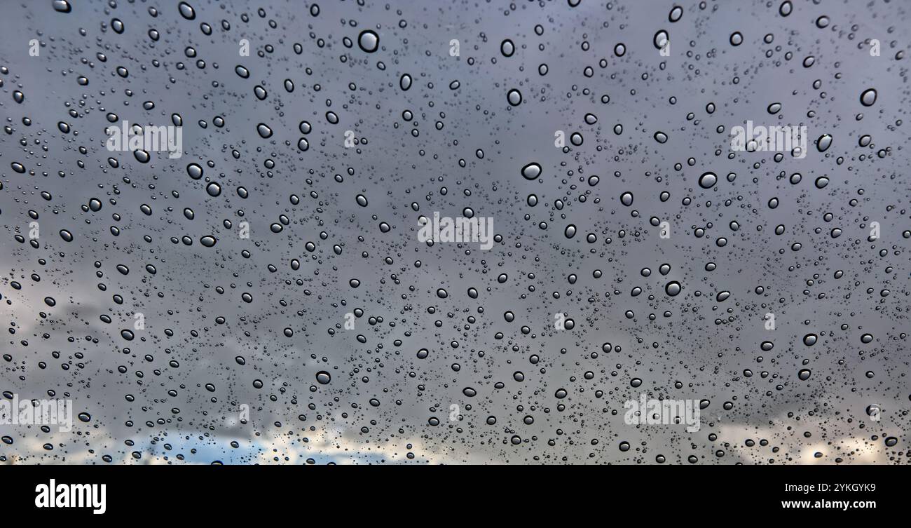 Zufällige Muster von Regentropfen sehen durch die Windschutzscheibe eines Autos. Stockfoto