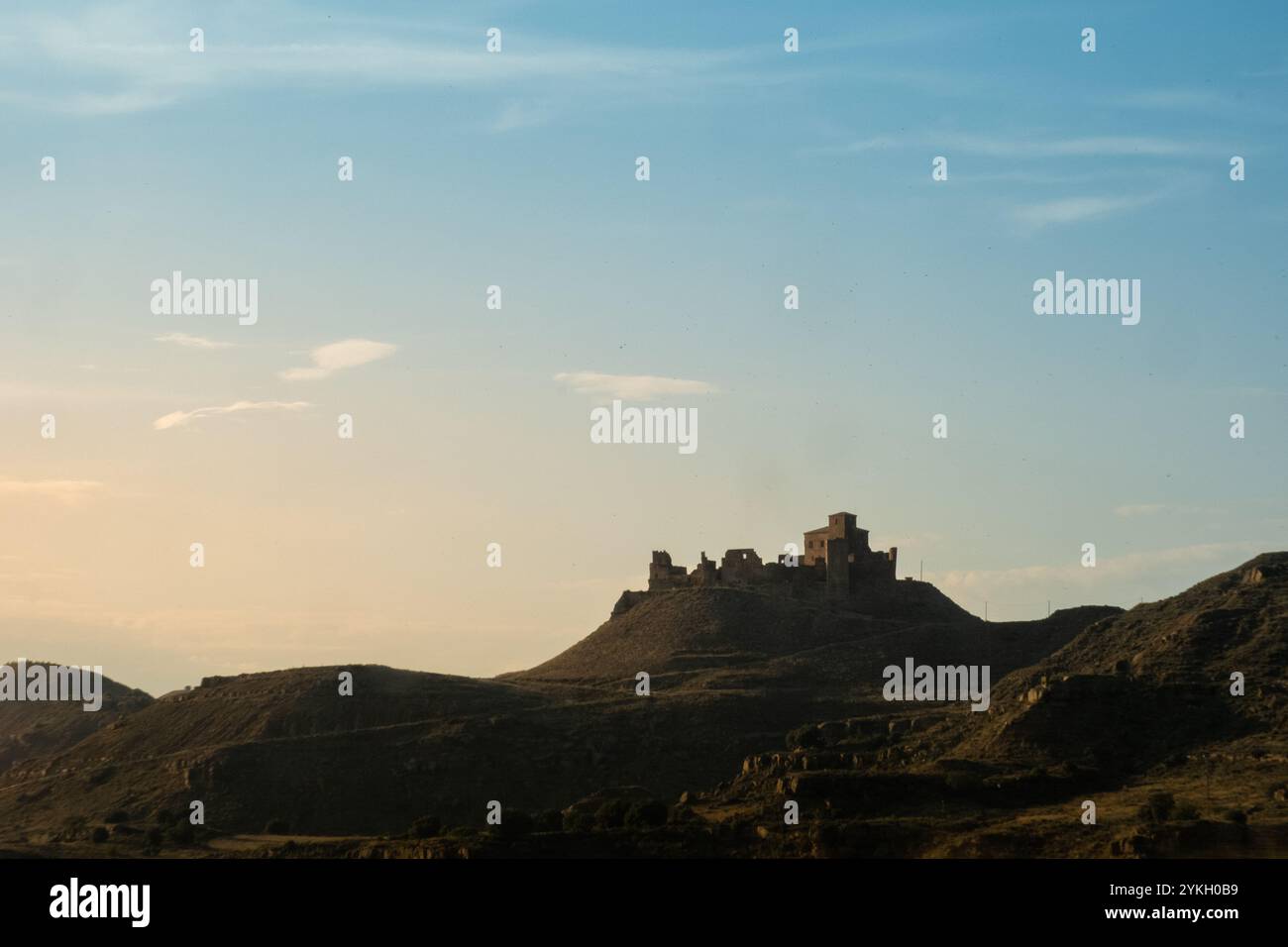 Sonnenuntergang mit klarem Himmel. Der Berg zeichnet die Silhouette der alten mittelalterlichen Burg von Montearagon in Ruinen. Man kann die Wand und ein paar Well-Pres sehen Stockfoto