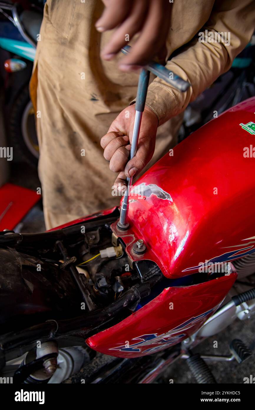 Nahaufnahmen einer Motorradwerkstatt im SWAT Valley, Pakistan, bei der Werkzeuge, Fahrräder und erfahrene Mechaniker bei der Arbeit erfasst werden۔ Stockfoto