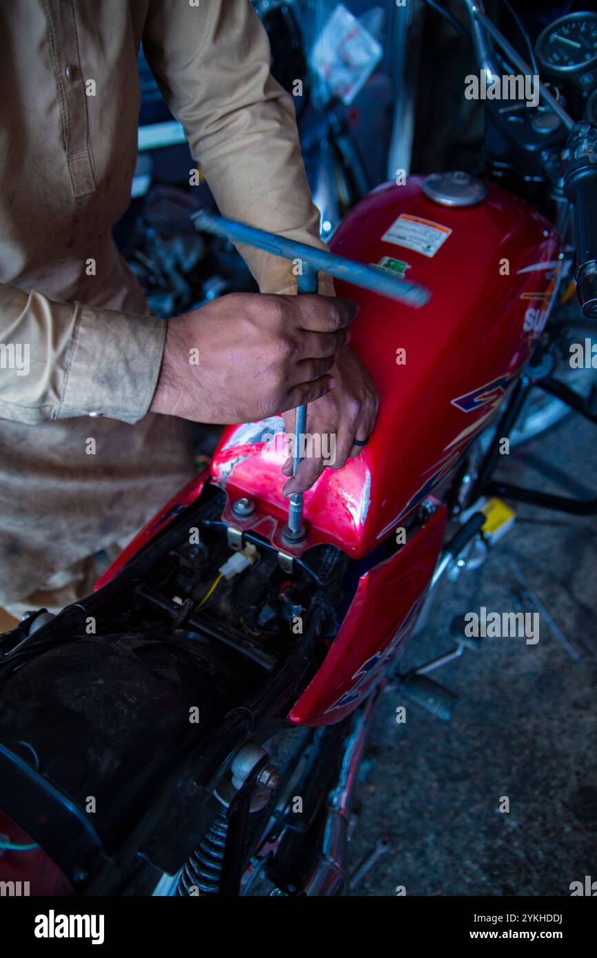 Nahaufnahmen einer Motorradwerkstatt im SWAT Valley, Pakistan, bei der Werkzeuge, Fahrräder und erfahrene Mechaniker bei der Arbeit erfasst werden۔ Stockfoto