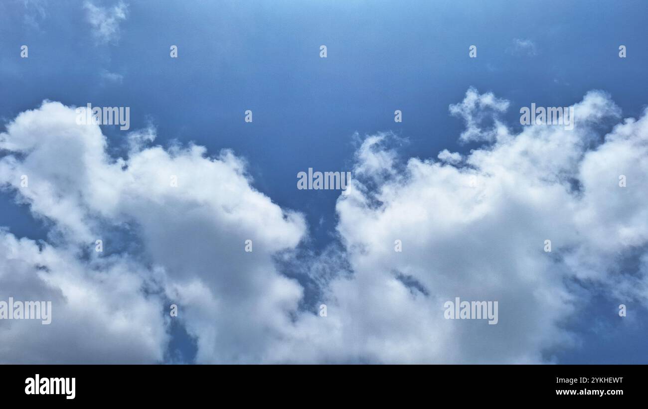 Die Schönheit eines hellblauen Himmels mit weißen Wolken, die an Baumwolle erinnern. Diese Wolken bilden einen schönen Kontrast zum blauen Hintergrund. Stockfoto