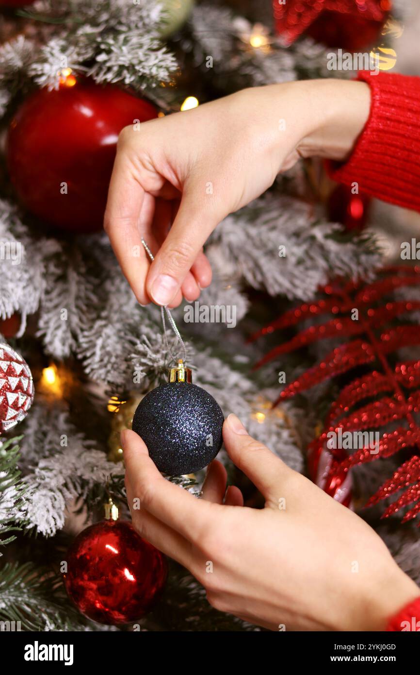 Weihnachtsbaum, Neujahrskonzept. Weibliche Hände hängen Spielzeug an den Weihnachtsbaum. Neujahrsvorbereitung, Dekoration, Weihnachtsbaumkugeln. Weibliche Vorbereitung Stockfoto