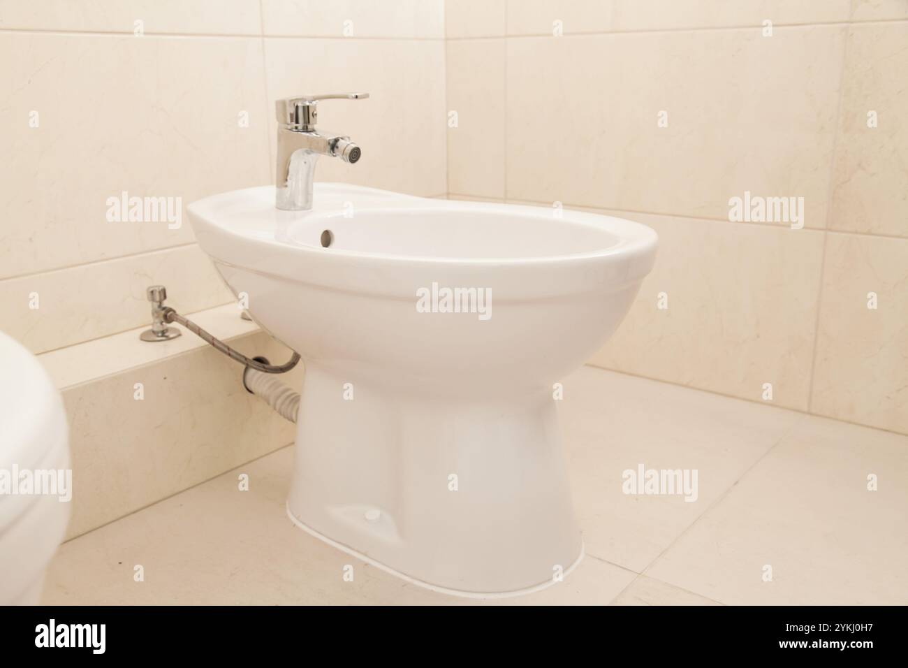 Weißes Bidet im Badezimmer, beige Fliesen. Ruhiges Luxuskonzept Stockfoto