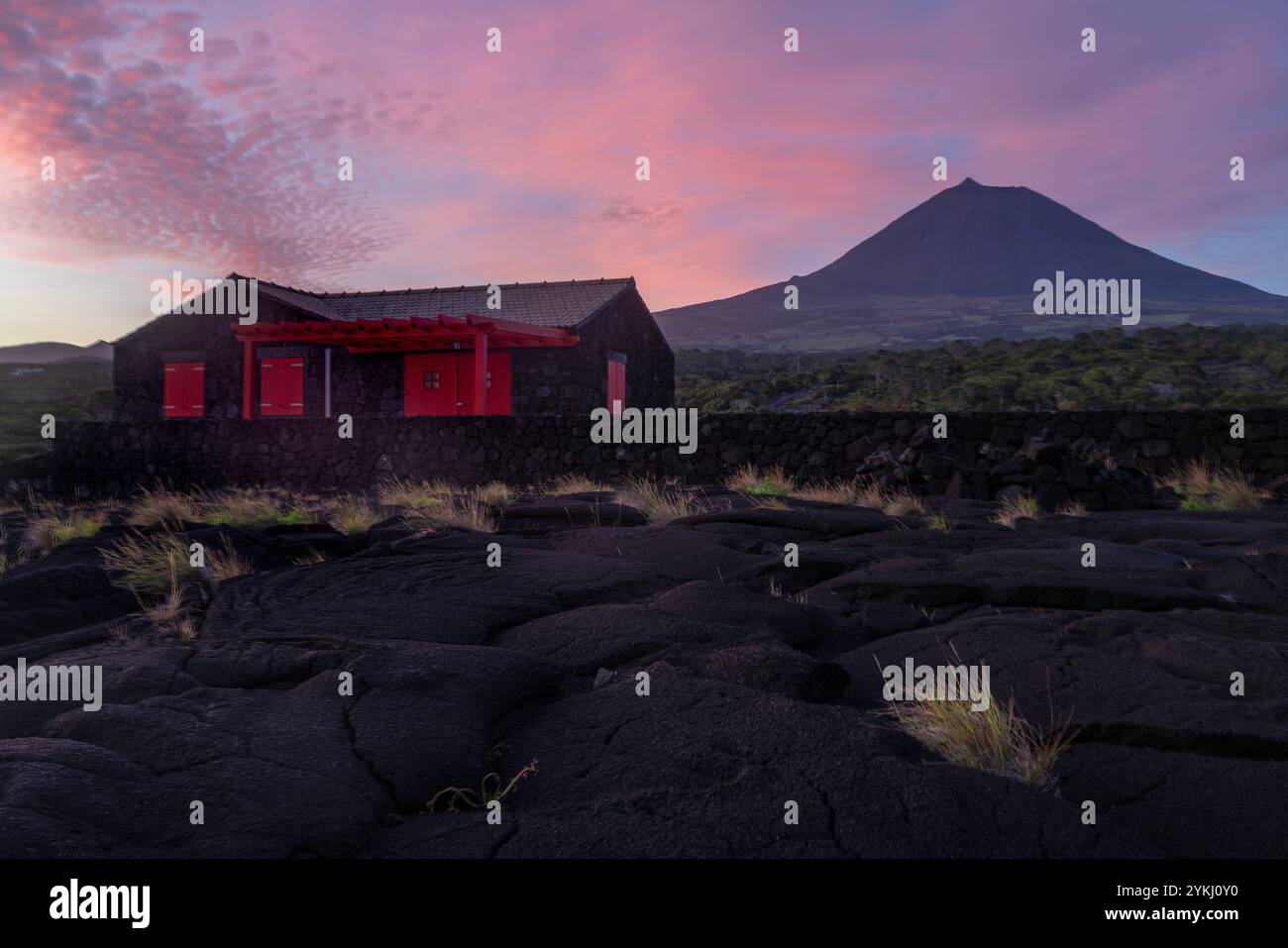 Cabrito auf der Insel Pico auf den Azoren hat einen Badebereich aus schwarzer Lava mit traditionellen Lavasteinhäusern mit Blick auf den majestätischen Mount Pico. Stockfoto