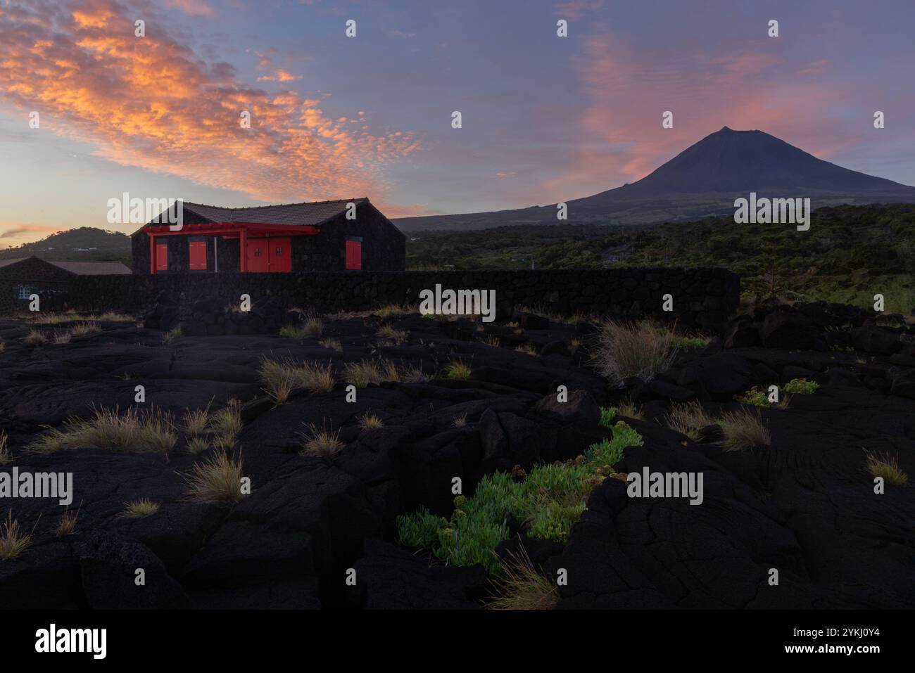 Cabrito auf der Insel Pico auf den Azoren hat einen Badebereich aus schwarzer Lava mit traditionellen Lavasteinhäusern mit Blick auf den majestätischen Mount Pico. Stockfoto