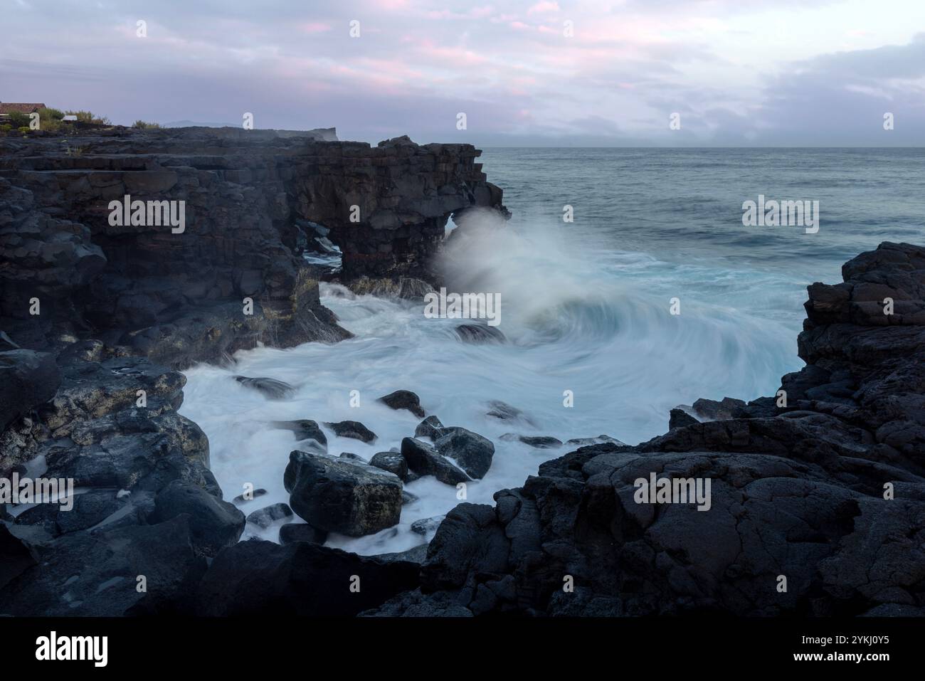 Cabrito auf der Insel Pico auf den Azoren hat einen Badebereich aus schwarzer Lava mit traditionellen Lavasteinhäusern mit Blick auf den majestätischen Mount Pico. Stockfoto