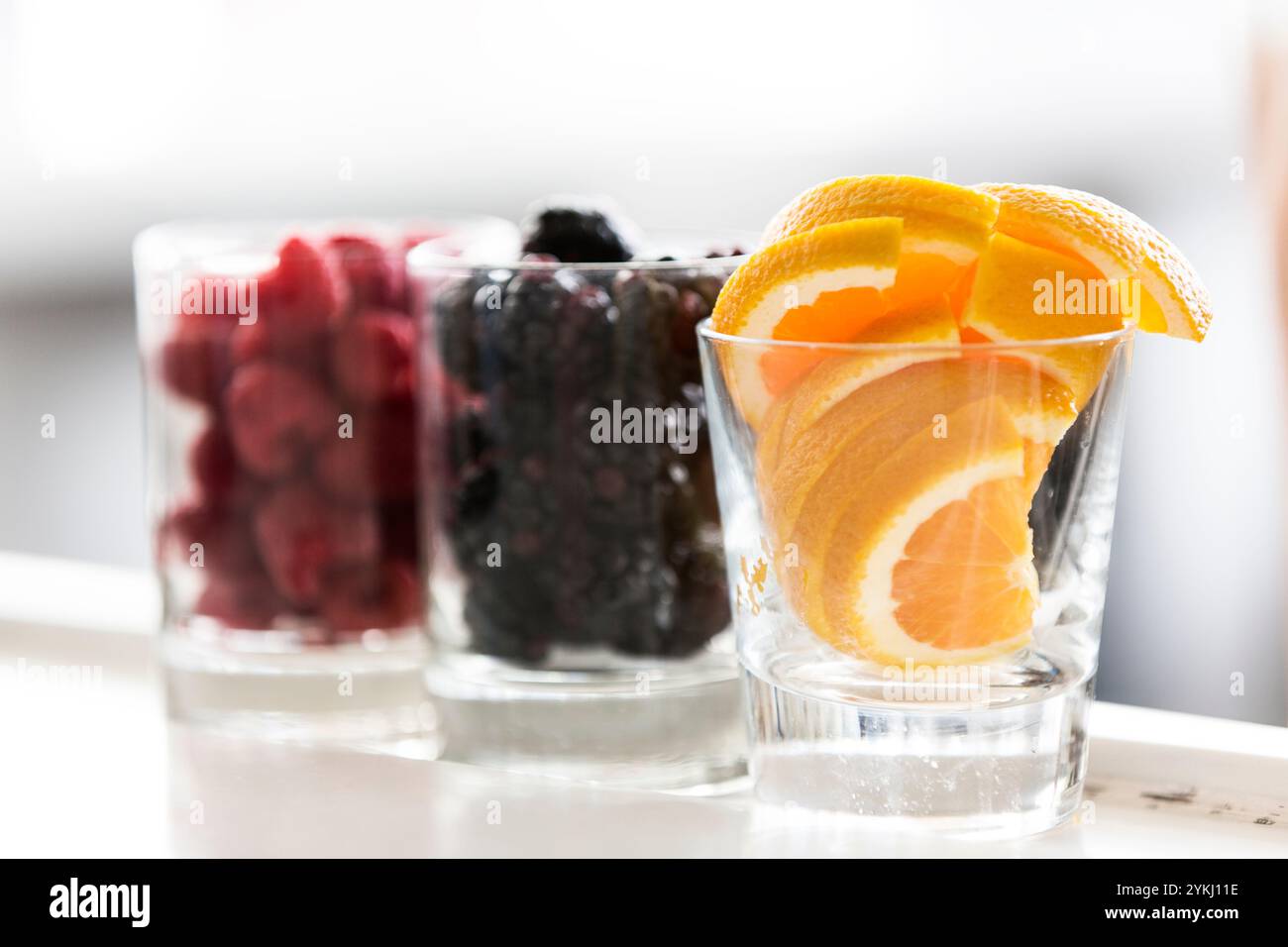Frische Beeren und Orangenscheiben in Glasbechern Stockfoto