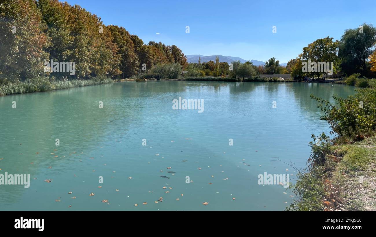 „Herbstruhe in der Nähe von Shiraz, Iran: Ruhiges türkisfarbenes Wasser spiegelt lebendiges Laub und klaren Himmel wider und bietet einen ruhigen Rückzugsort in der Natur.“ Stockfoto