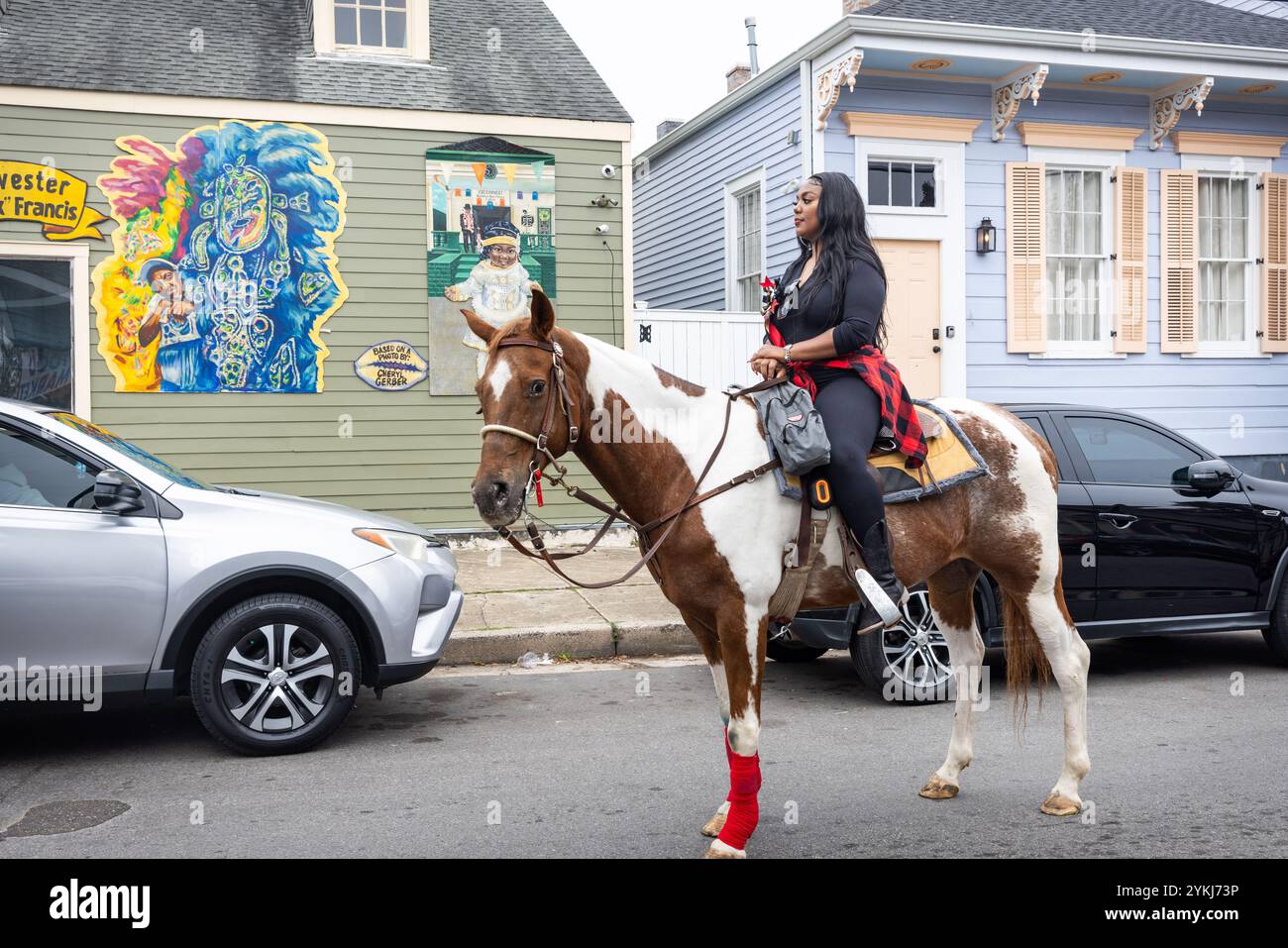 Frau zu Pferd beobachtet die Second Line Parade, die durch die Straßen des Treme-Viertels in New Orleans, Louisiana, zieht. Stockfoto