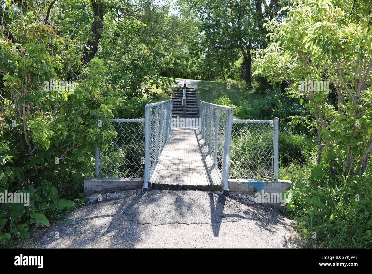 Eine schmale Fußgängerbrücke führt zu Treppen, die eine Treppe hinauf führen Stockfoto