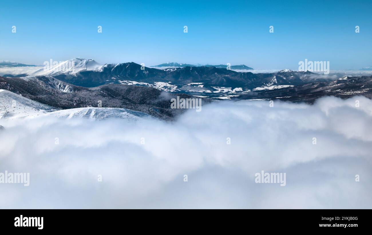 Hoch aufragender, schneebedeckter Vulkan über einer Wolkenschicht (Mount Asama) Stockfoto