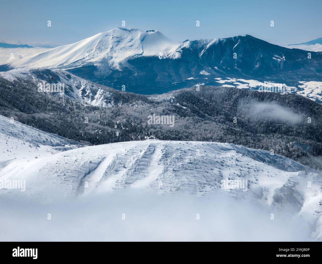 Hoch aufragender, schneebedeckter Vulkan über einer Wolkenschicht (Mount Asama) Stockfoto