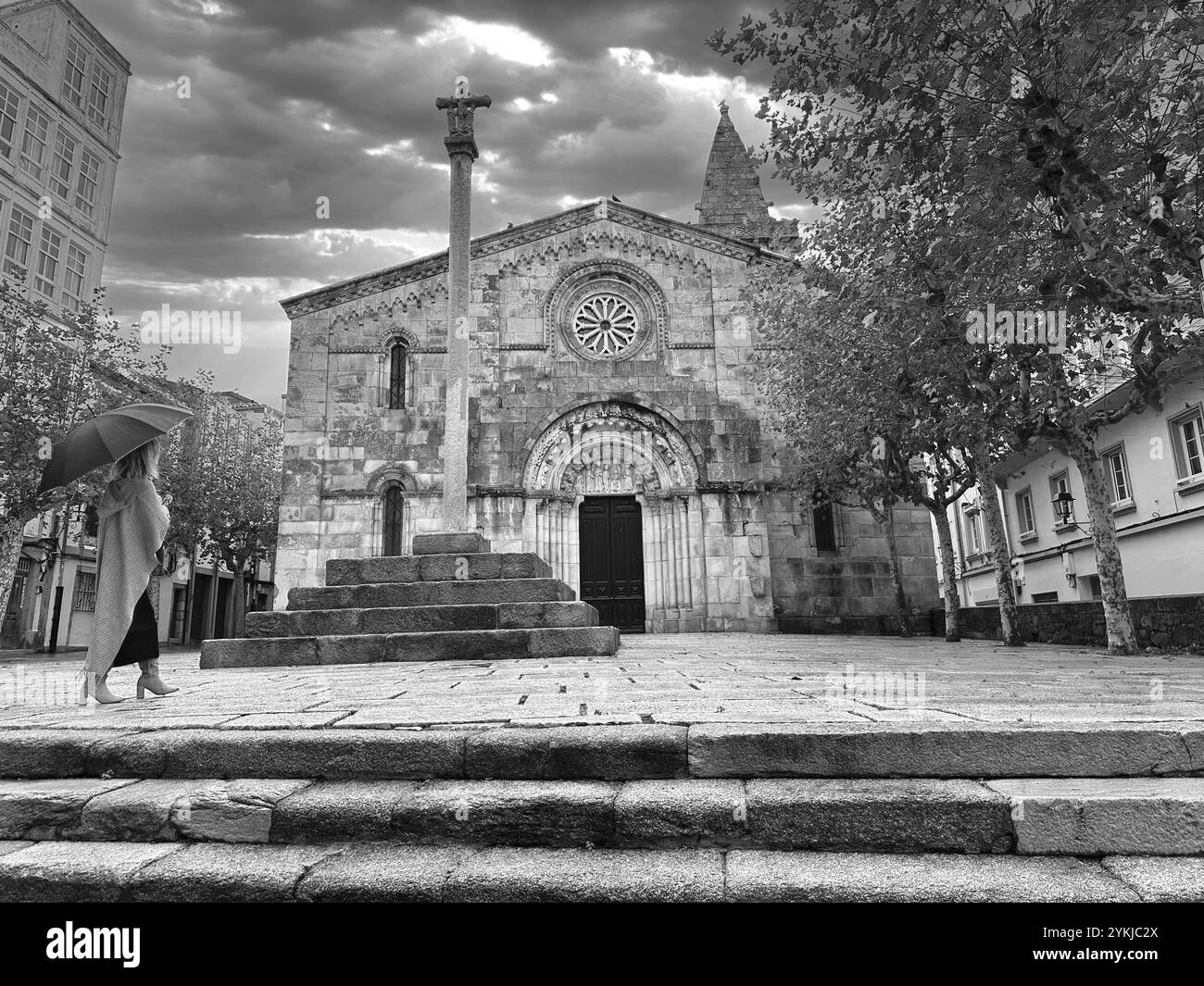 Frau mit Schirm, die in Richtung der alten Kirche, A Caruña, Galicien, Spanien geht Stockfoto