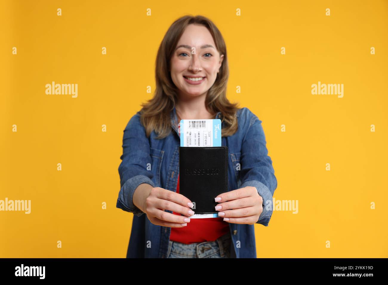 Glücklicher Reisender mit Pass und Ticket auf gelbem Hintergrund, selektiver Fokus Stockfoto