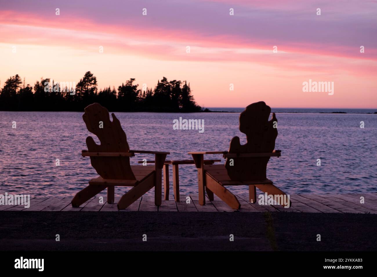 Zwei Adirondack-Stühle auf einem Dock in der Form des Bundesstaates Michigan am Ufer des Lake Superior bei Sonnenuntergang Stockfoto