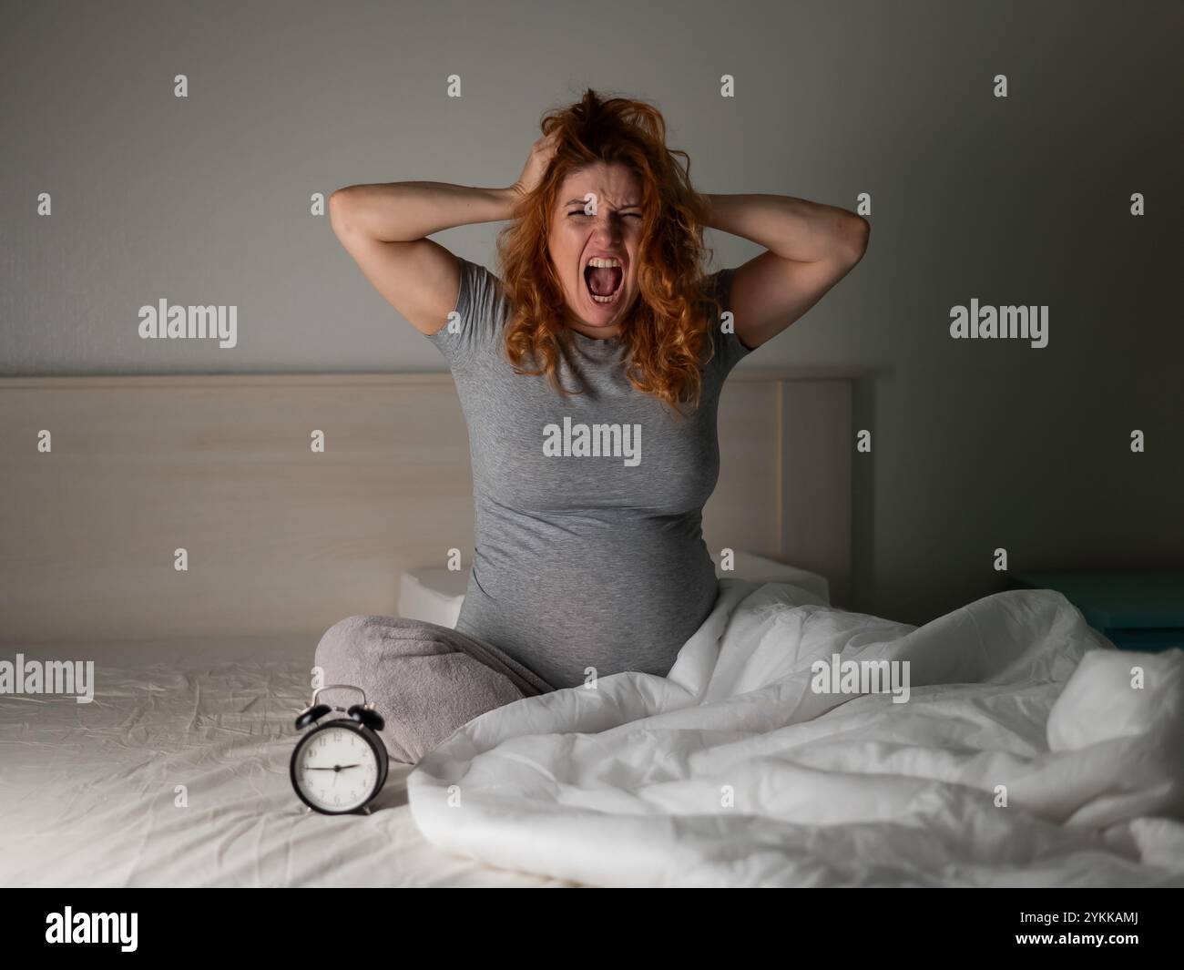 Kaukasische Schwangere sitzend und schreiend, während sie an Schlaflosigkeit litt. Stockfoto