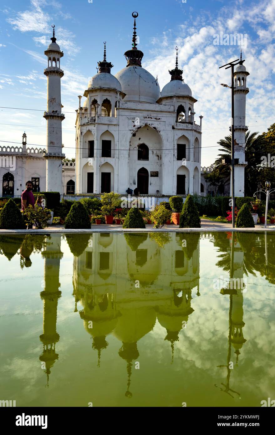 Ruhiger Blick auf eine weiße Moschee mit ihrer Reflexion, die sich in einem ruhigen Wasserpool während der goldenen Stunde spiegelt Stockfoto